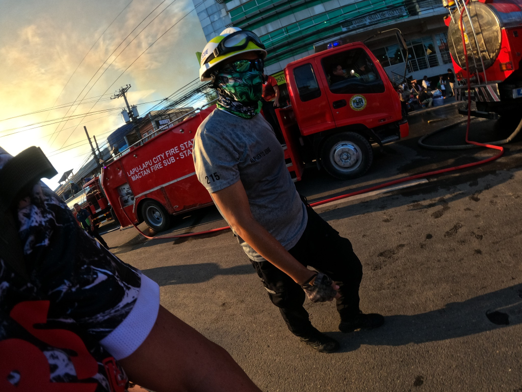 Photo: Bart Sakwerda. foudner of BDUOTS MEDIA PH. 

Firefighter in brgy PUSOK, LAPULAPU CITY wlaking. Smoe in the background, cinematic feel, cinematic colors. 